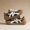 Ein Paar braune und beige minimalistische Sneaker mit weißen Akzenten, von der Seite gezeigt.