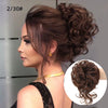Primer plano de una mujer con cabello castaño en un moño rizado despeinado y natural.