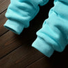 Light blue fleece pajama pants and sleeves laid on a dark wooden surface.