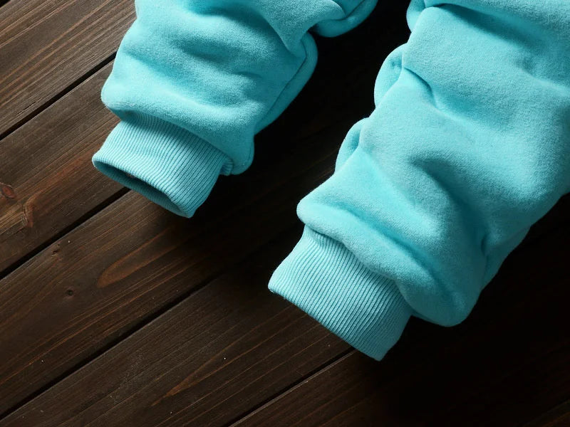 Light blue fleece pajama pants and sleeves laid on a dark wooden surface.