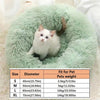 A fluffy mint green pet bed shaped like a donut with a white kitten resting inside.