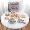 A wooden pretend play kitchen set with pots, pans, and play food displayed on a white table.