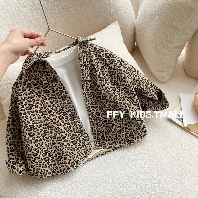 A leopard print denim jacket is displayed on a hanger against a light background.