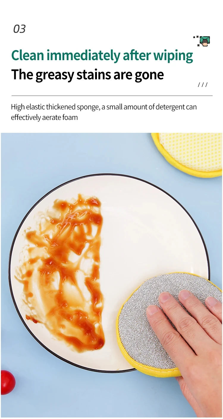 A hand is using a yellow scouring pad to clean greasy stains from food on a white plate.