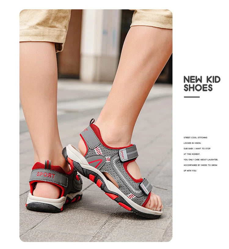 A close-up of a pair of gray and red kids' sport sandals worn on a person's foot.