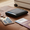 A brown leather travel bag with a black card holder and a passport resting on it.