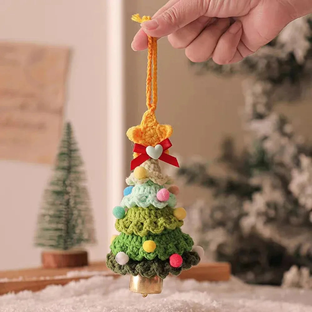 Hånd som holder en håndlaget strikket juletrepynt med en jinglebjelle dinglende.