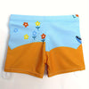 Light blue swim trunks for boys featuring a floral pattern and an orange lower section.