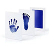 A white framed print showing a blue handprint and footprint on the left, next to a blue framed print with a dark blue backgro