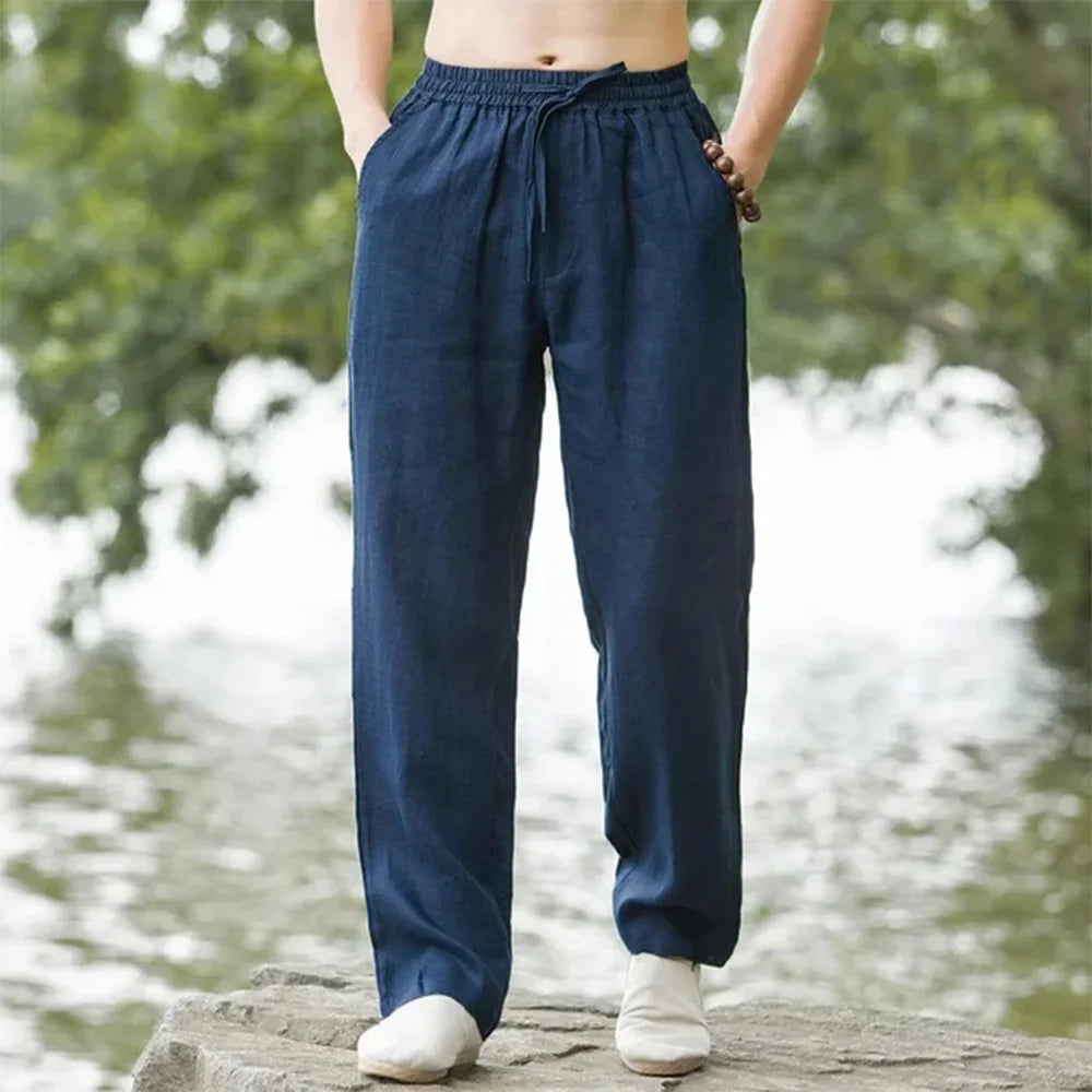 A pair of dark navy blue men's cotton linen casual jogger pants being held up by the wearer.