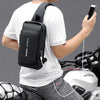 Hombre con bolso bandolero negro antirrobo y puerto USB sobre camiseta blanca.