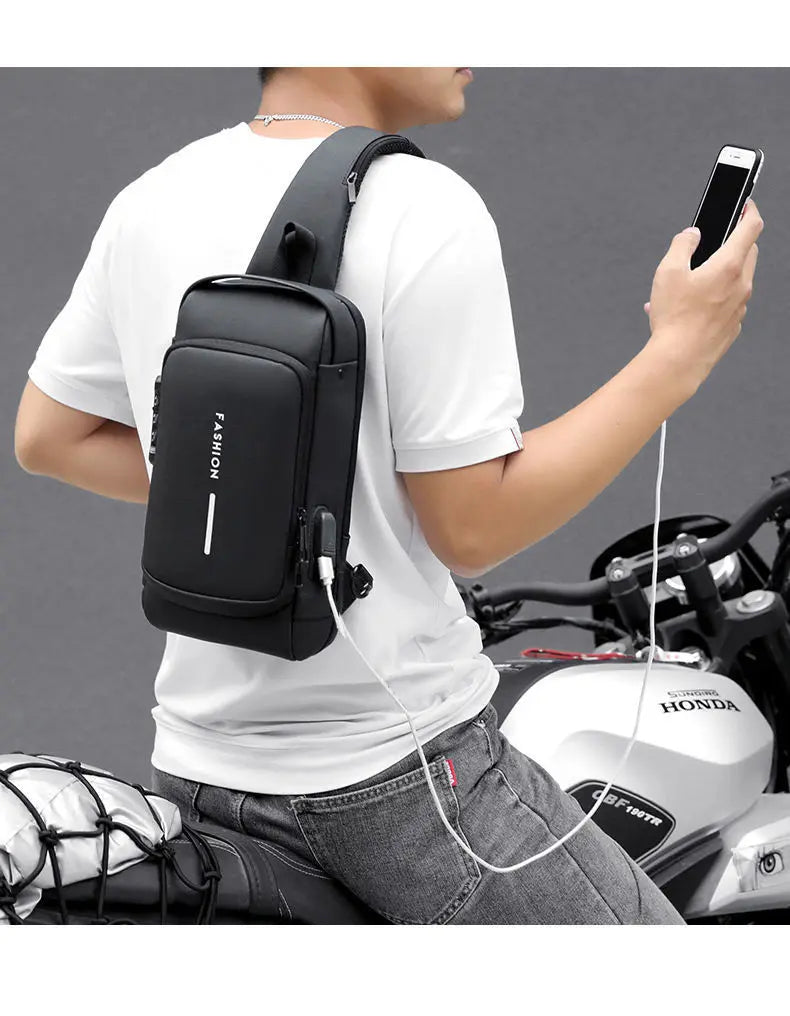 Hombre con bolso bandolero negro antirrobo y puerto USB sobre camiseta blanca.