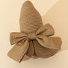 A beige straw sun hat with a wide ribbon bow, shown against a light background.