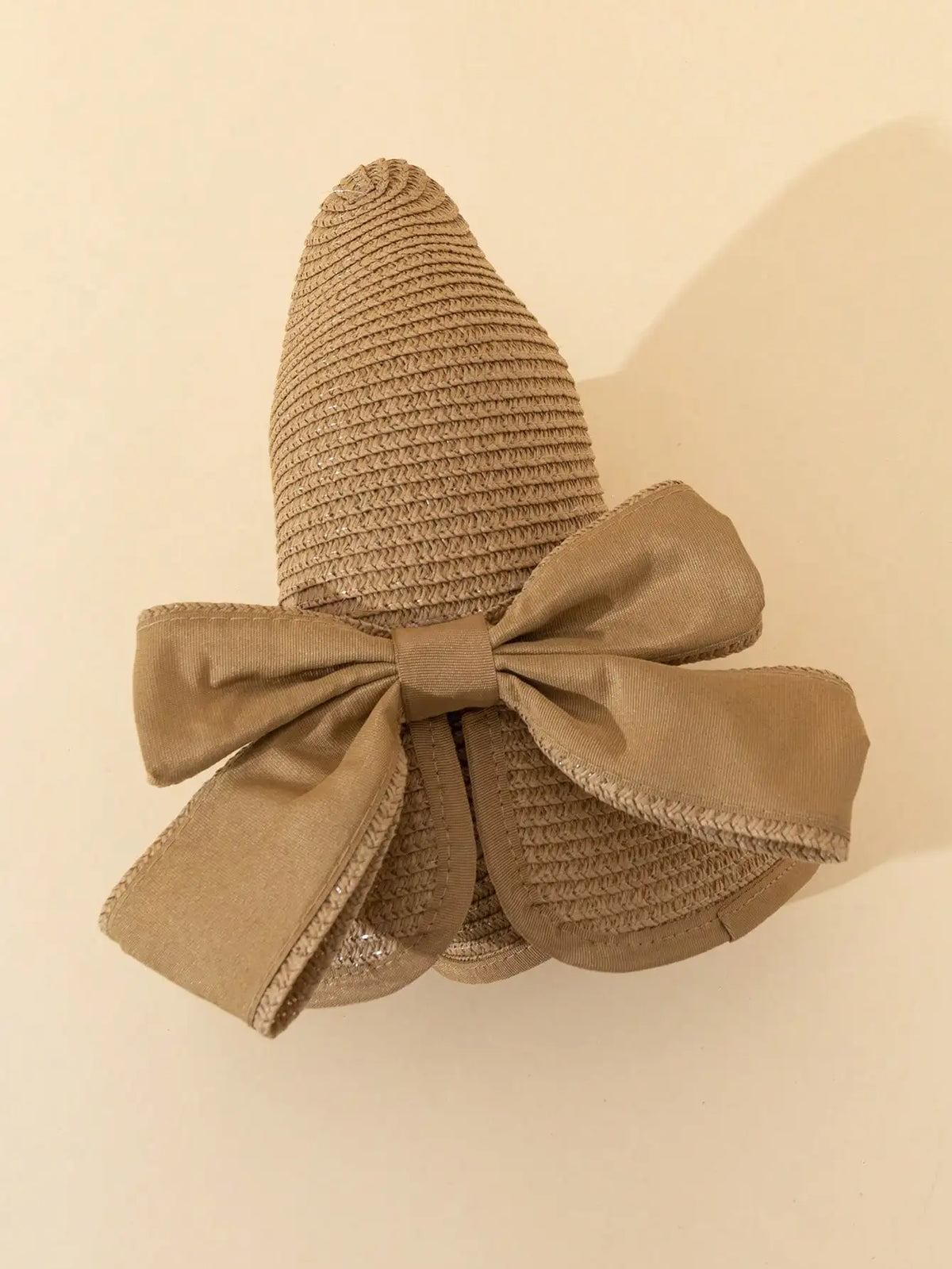 A beige straw sun hat with a wide ribbon bow, shown against a light background.