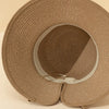 A close-up view of an elegant straw sun hat in a beige color with a woven texture.