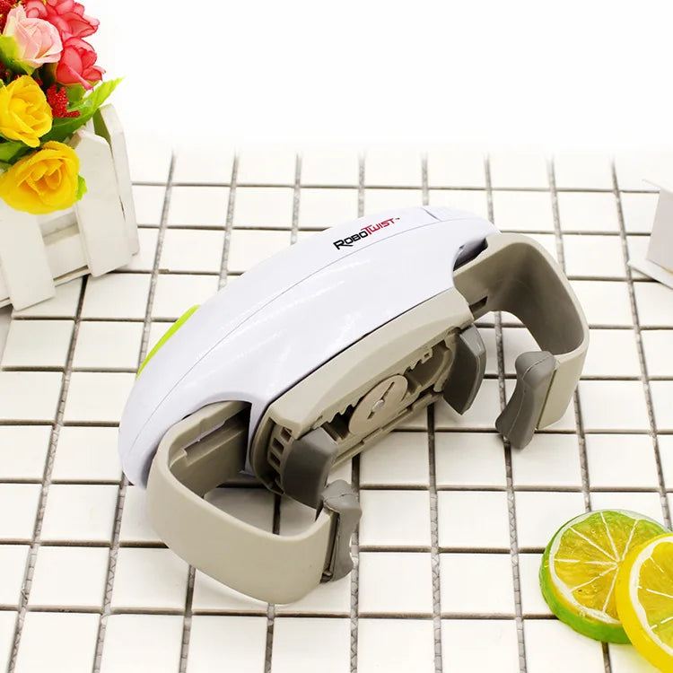 A white automatic electric can and jar opener device resting on a white tiled surface next to flowers.