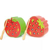 A red strawberry shaped magnetic wooden game piece with green and yellow details.