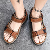 Pair of brown men's genuine leather air cushion sandals worn on a gray pavement.
