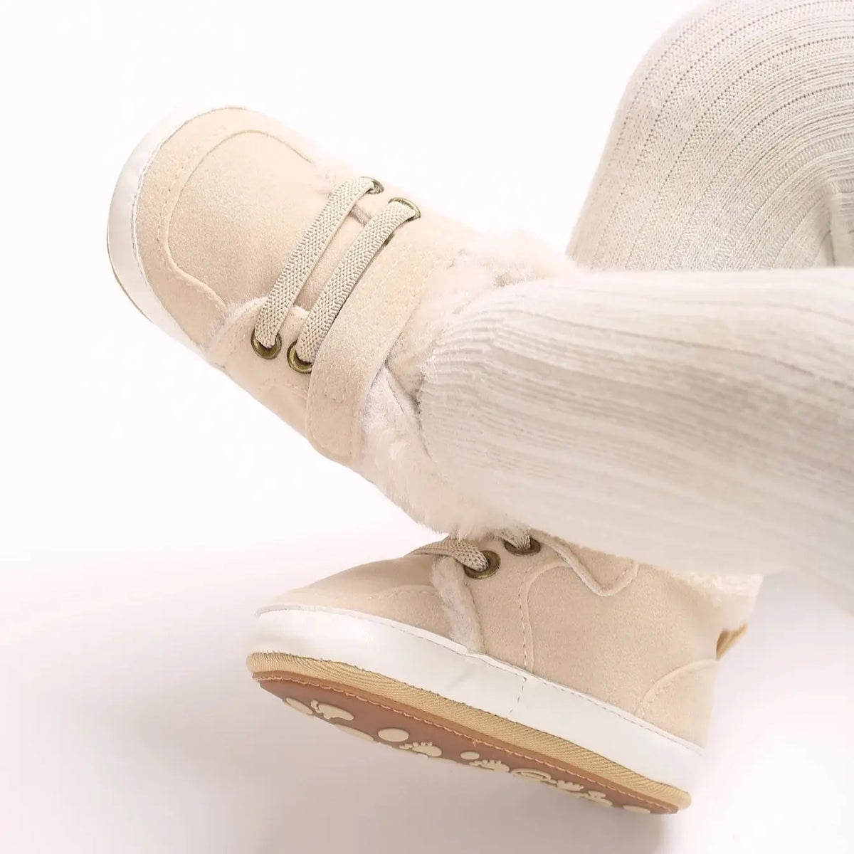 A close-up of beige soft cotton baby winter snow boots for toddlers, showing the sole and upper material.