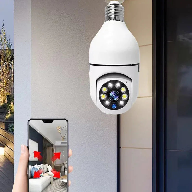 A white security camera with a visible lens is mounted on a wall, next to a hand holding a smartphone displaying a mirror ref