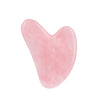 Rodillo de jade o herramienta gua sha en forma de corazón translúcido rosa para masaje facial y cuidado de la piel.