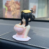 Liten animefigur av en jente med svart hår og gult pannebånd, vist på en mørk overflate.
