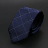 Corbata azul oscuro con patrón de cuadrícula sutil, doblada sobre fondo oscuro.