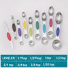 A set of nine stainless steel double-headed measuring spoons with various tablespoon and teaspoon sizes displayed on a white 