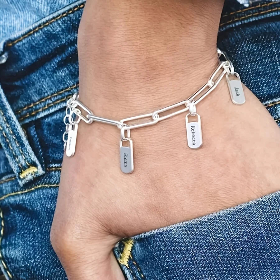 Primer de pulsera de nombre de acero inoxidable bañado en oro con cadena ajustable y dijes, usada en la muñeca.