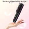 A hand holds a black hair straightening brush with a pink accent, demonstrating its use.