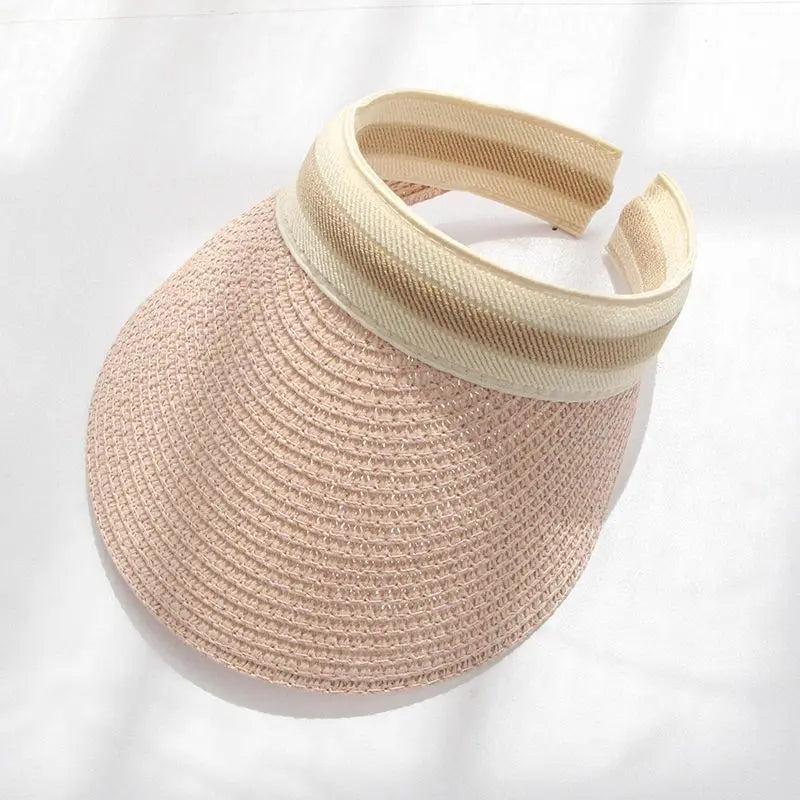 A woven straw sun hat in a light pink color with a beige band for women.