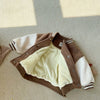 A brown corduroy jacket with white sleeves and a cream fleece lining is laid flat on a light surface.