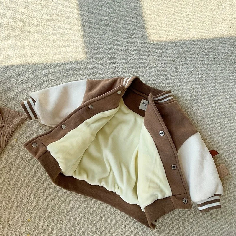 A brown corduroy jacket with white sleeves and a cream fleece lining is laid flat on a light surface.