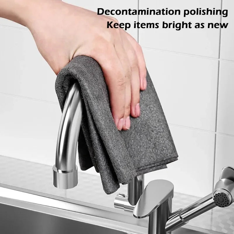 Eine Hand reinigt einen Wasserhahn mit einem dunkelgrauen Mikrofasertuch.