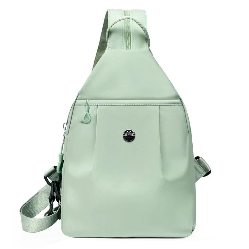 A light mint green lightweight oxford cloth mini backpack with a drawstring closure.