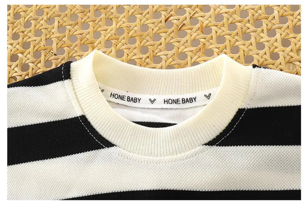 A close-up of a white and black striped short set with a collared tee laid on a woven natural fiber background.