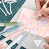 Seis bolígrafos de cúter de precisión con puntas de colores y cuchillas de repuesto sobre un dibujo técnico.