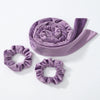 A purple velvet heatless curling rod headband rolled into a spiral and a separate matching headband are shown.