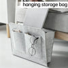 Organizador colgante de fieltro gris con múltiples bolsillos dentro de un armazón de cama de madera.