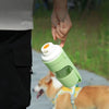 Una mano sostiene un botellero portátil verde para perros con compartimento de comida al aire libre.