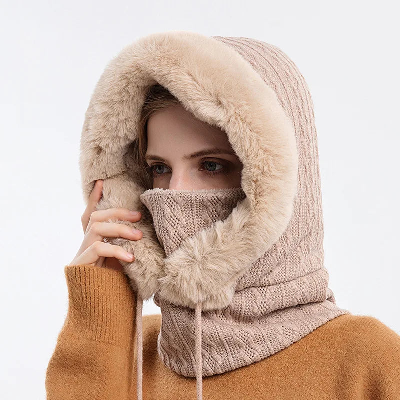 A woman wearing a beige knitted hooded scarf with a faux fur trim and face mask.