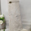 A beige knee-high boot with a chunky heel and a gold metal buckle.
