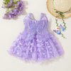 A purple tulle butterfly dress for a baby girl displayed on a light background with lavender flowers and a straw hat.