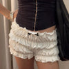 A woman is wearing white ruffled tiered shorts with a black bow detail and a black top.