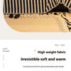 A close-up of a black and white striped chenille sofa blanket draped over a light wood surface.