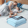A baby is resting on a light blue breathable cooling throw blanket while being held by a woman.