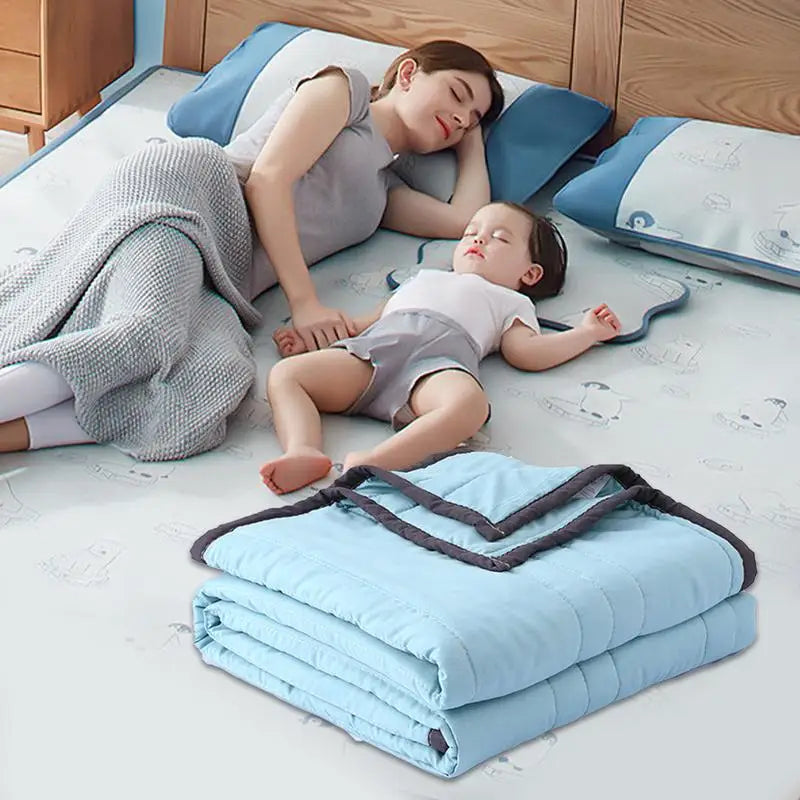 A baby is resting on a light blue breathable cooling throw blanket while being held by a woman.