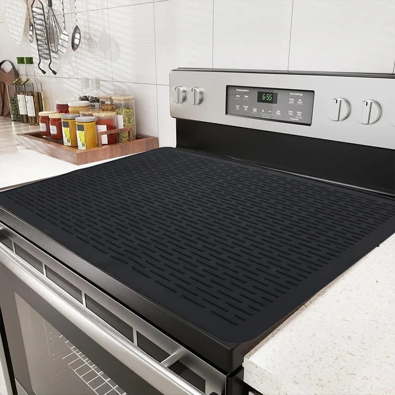 A black silicone stove protector mat is shown resting on a stovetop, with a digital timer display visible.
