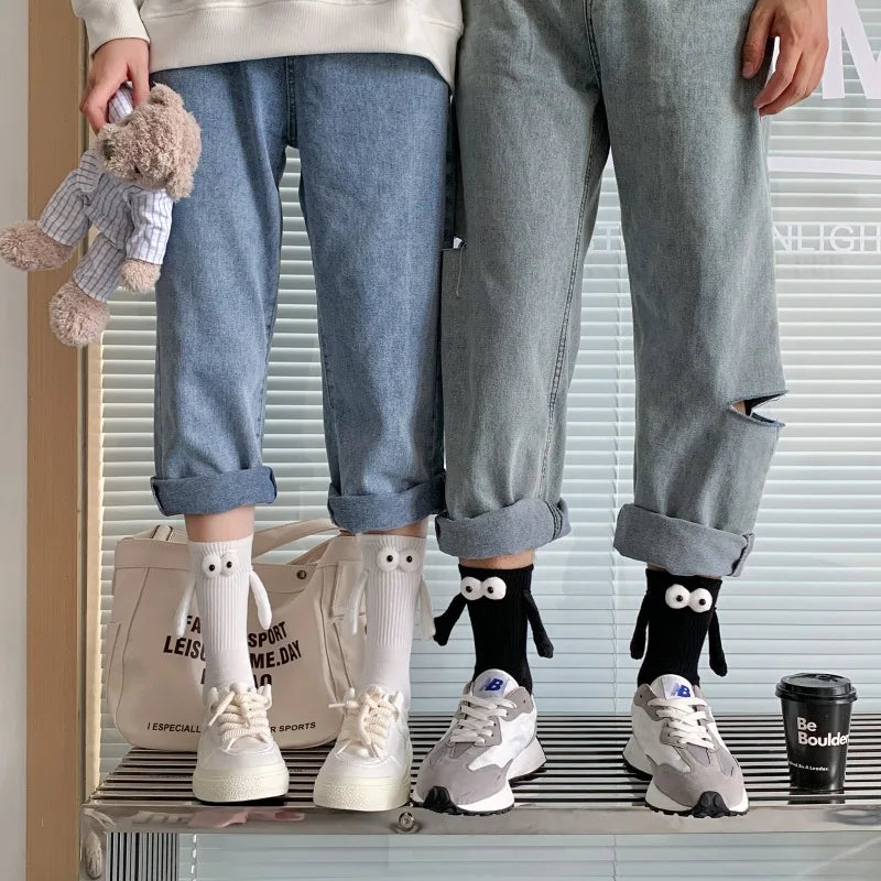 A pair of light gray jeans and a person wearing white boots with cartoon hand designs.