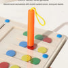 An orange wooden tower with a yellow string is placed on a light-colored board featuring colorful magnetic discs.